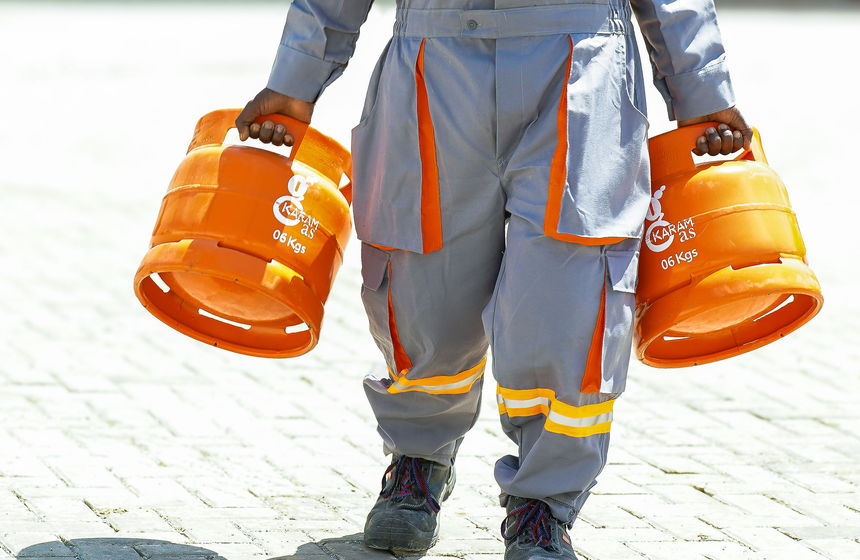 A Karam Gas worker carrying two new 6 kg cylinders